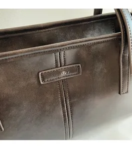 Detailed close-up of dark brown vintage leather tote bag showing fine stitching and logo patch