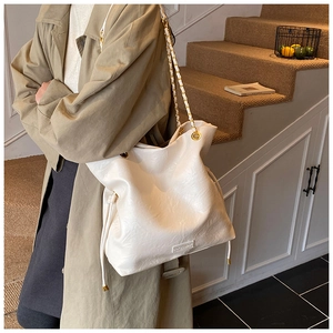 Close-up of off-white pleated leather bucket bag with gold chain and metal logo detail