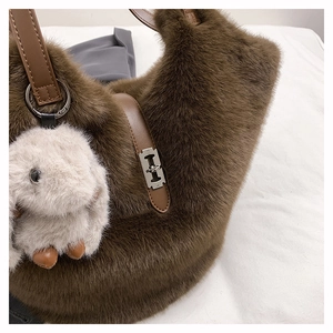 Detail of plush brown tote bag with leather handles and silver H-shaped rotating metal lock