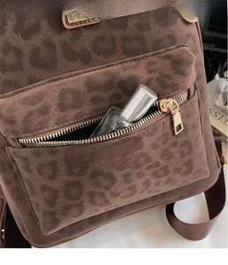 Détail d'un sac à dos léopard montrant une fermeture éclair dorée sur la poche