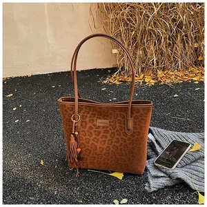 Detail of leopard print tote bag with brown tassel charm and beaded accessory decoration