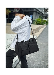 Close-up of black nylon travel bag featuring dual front pockets and thick woven handles
