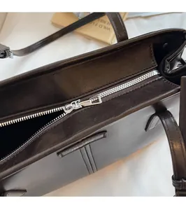 Detailed close-up of the smooth silver zipper and leather texture on a coffee Boston bag