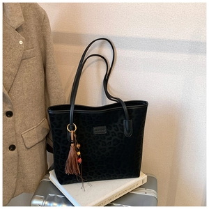 Detail shot of leopard pattern tote bag with decorative tassel on a vintage silver suitcase