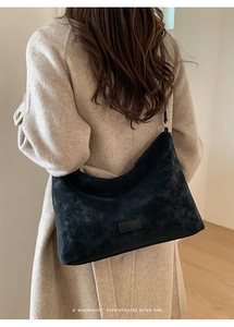 Détail du sac à bandoulière rétro minimaliste en daim noir porté par un mannequin