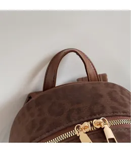 Détail d'un sac à dos léopard avec poignée en similicuir et fermeture éclair en métal doré