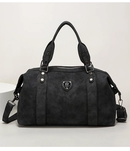 Detail view of dark grey retro leather boston bag with a metallic shield logo and handles