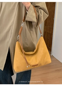 Détail d'un sac fourre-tout minimaliste en daim jaune moutarde avec bandoulière en cuir