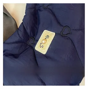 Close-up of heart-shaped quilting on dark blue tote bag with pearl detail and embroidery