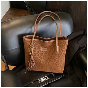 Detail of leopard print tote bag with fringe tassel on a leather chair setting