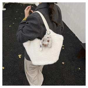 Detailed view of white plush tote bag with grey rabbit pendant on ginkgo leaf background