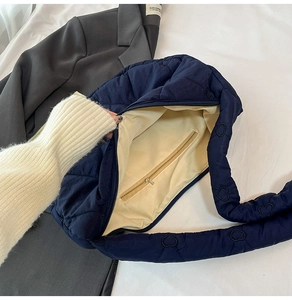Detail view of navy blue quilted heart pattern tote bag with zip pocket and beige lining