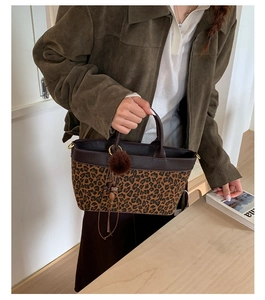 Dettaglio borsa leopardata con pompon di peluche e nappe su tessuto vintage
