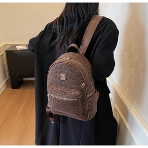Détail du sac à dos léopard avec fermeture dorée et logo porté par un modèle