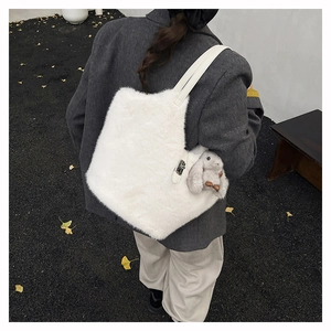 Detail of white plush tote bag texture with cute rabbit charm and leather shoulder strap