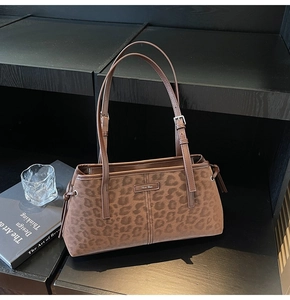 Detail of leopard print shoulder bag with adjustable strap on a wooden display
