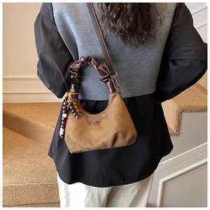 Detail of retro brown suede handbag with pleated handle and colorful beaded charm