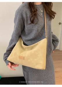 Détail du sac hobo beige minimaliste avec texture mate et écusson logo en cuir
