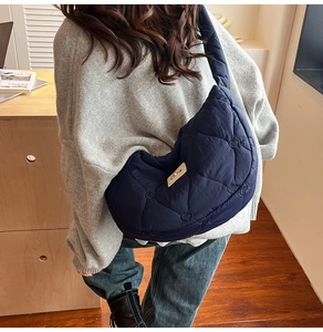 Detail of navy blue quilted shoulder bag featuring heart patterns and soft cotton strap