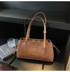 Detail of a brown PU leather shoulder bag with metallic logo and adjustable thin straps
