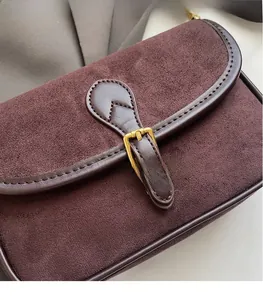 Detailed macro view of dark brown frosted suede texture and golden buckle on the bag