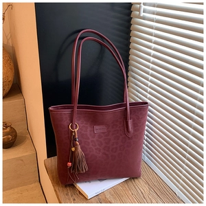Detailed view of burgundy leopard pattern tote bag with decorative tassel and beads
