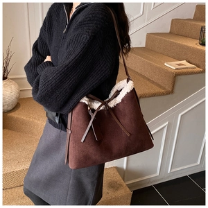 Detailed view of brown suede bucket bag with white shearling trim and bow tie decoration