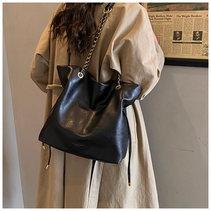 Detail of black faux leather tote with golden chain strap and drawstring closure