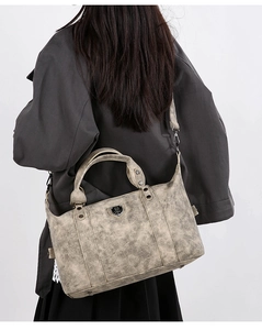 Detailed view of vintage textured tote bag with shoulder strap worn by a female model