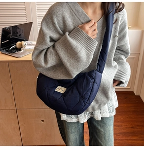 Detailed view of heart-shaped quilted navy crossbody bag with a logo label