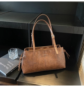 Detail of vintage brown tote bag with metal buckles on straps and side drawstring