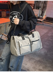 Detail view of a large grey nylon travel bag with functional pockets and shoulder strap