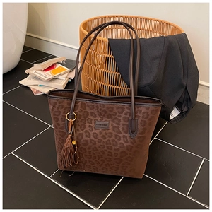 Detail of leopard print tote bag with suede texture and decorative side tassel charm
