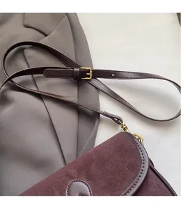 Detail of adjustable leather shoulder strap and gold hardware on retro crossbody bag