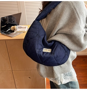 Detailed view of navy blue quilted puffer bag with heart stitching pattern on a model