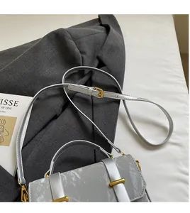 Detail of silver textured crossbody bag with gold hardware on dark suit jacket