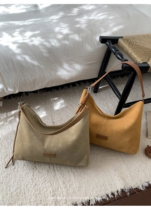 Détail de sacs hobo en daim vert olive et jaune avec bandoulières en cuir marron