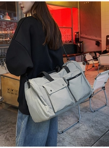 Detail of light grey nylon travel bag with reinforced handles and removable shoulder strap