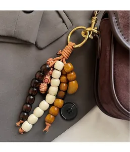 Detail of wooden bead charm with gold ring clasp on vintage matte brown crossbody bag