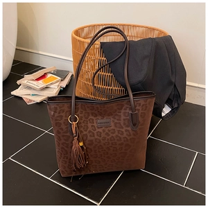 Detail of leopard print tote bag with suede texture and decorative tassel accessory