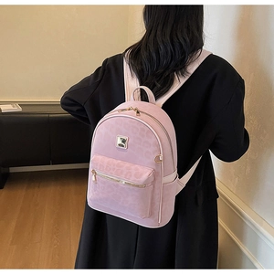 Détail du sac à dos rose à motif léopard avec finitions dorées porté par un mannequin