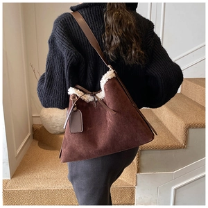 Close-up of deep brown suede tote with white faux shearling trim on model shoulder