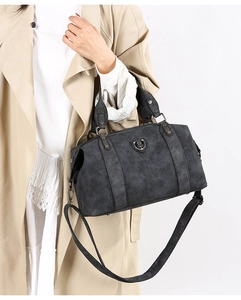 Detail of vintage washed leather Boston bag with metal emblem and adjustable strap