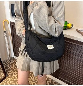 Detail of black heart-quilted crossbody bag showing soft nylon texture and large capacity