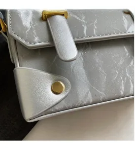 Detail of silver box handbag with glossy wave texture and gold metal hardware studs
