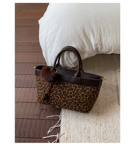 Dettaglio borsa leopardata con ciondolo a pompon di peluche e finiture in pelle