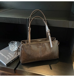 Detail of dark brown faux leather tote with adjustable shoulder strap and metal logo