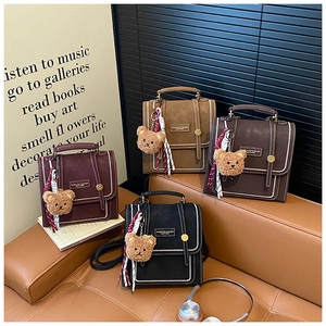 Detail of vintage PU leather backpacks with metal studs and teddy bear charms on a sofa