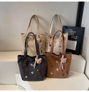 Close-up of four canvas tote bags with cute cat embroidery and plush bear charms