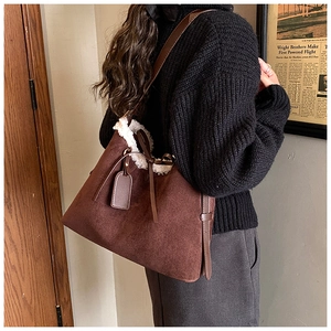 Detail of dark brown faux suede tote bag featuring plush white faux shearling trim